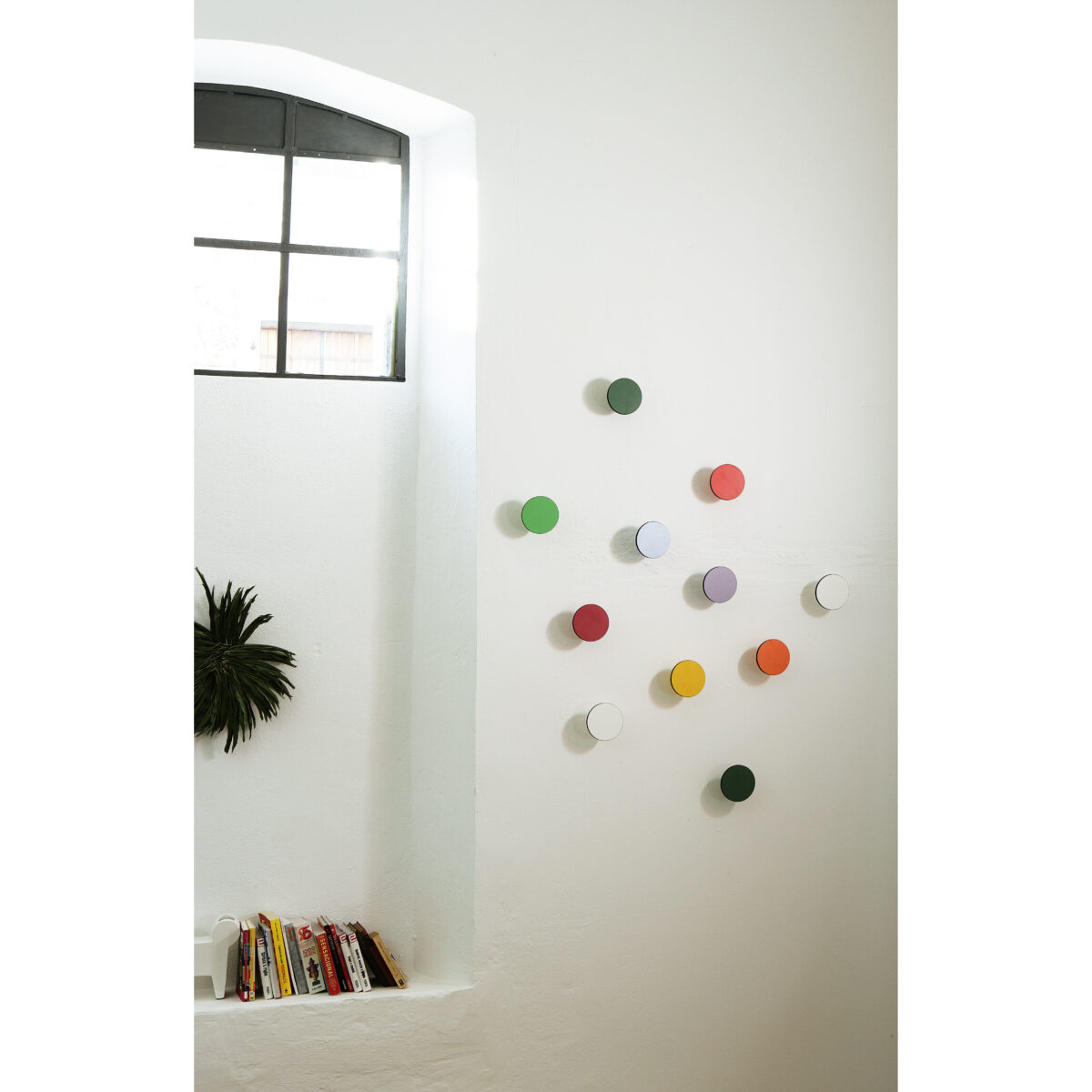 appendiabiti art up colorati posti in ordine sparso su una parete bianca