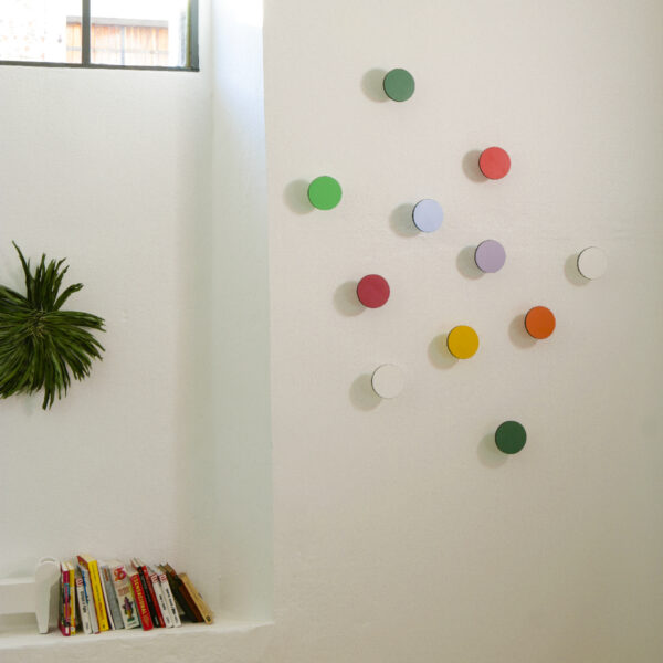 appendiabiti a muro colorati appesi in ordine sparso su una parete bianca