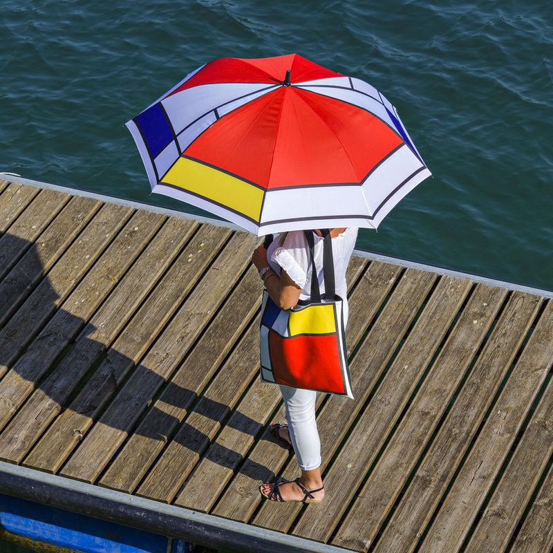 ragazza su molo con ombrello e borsa in coordinato motivo Mondrian