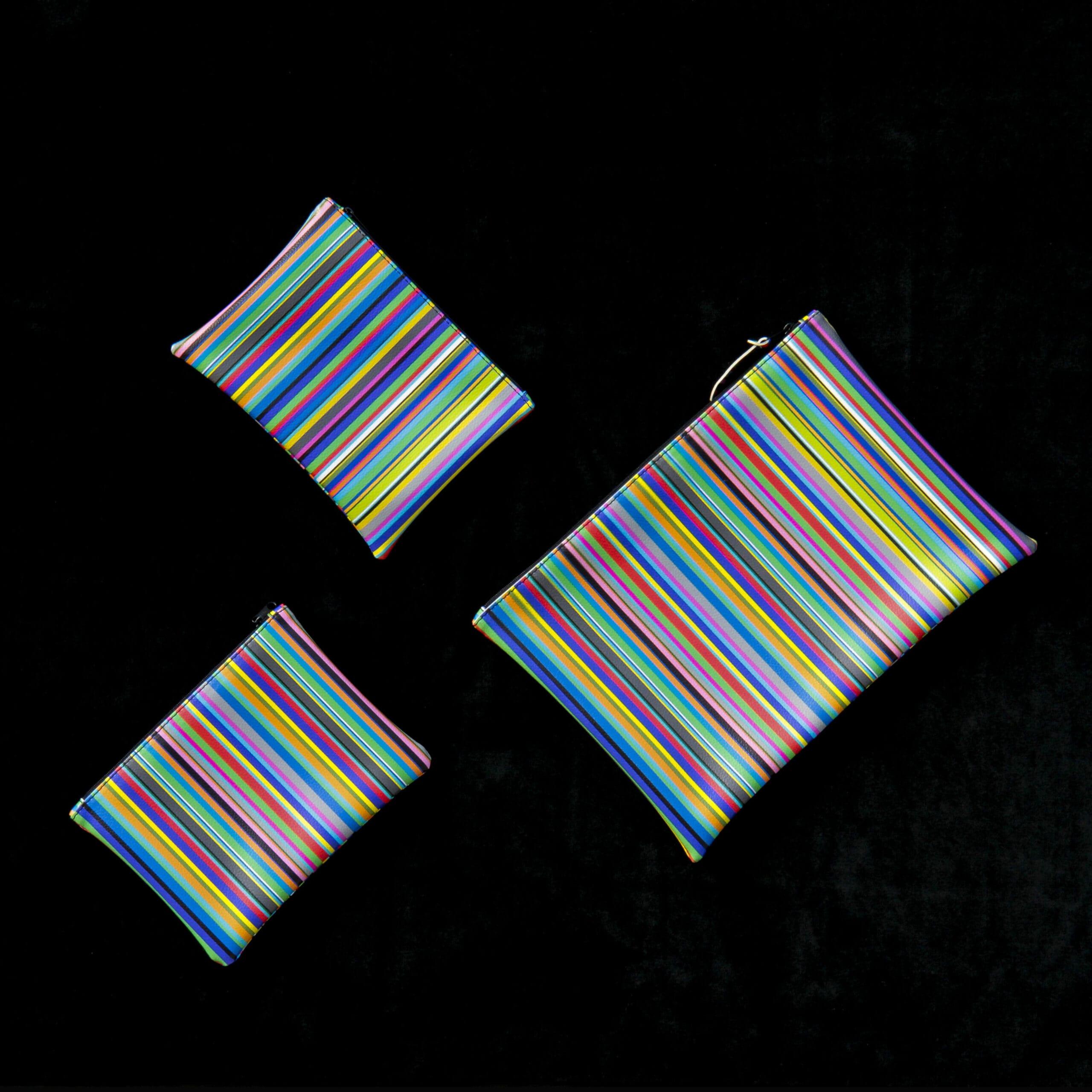 tre astucci di diverse dimensioni, di forma rettangolare, realizzati con tessuto a righe colorate disposti uno accanto all'atro.