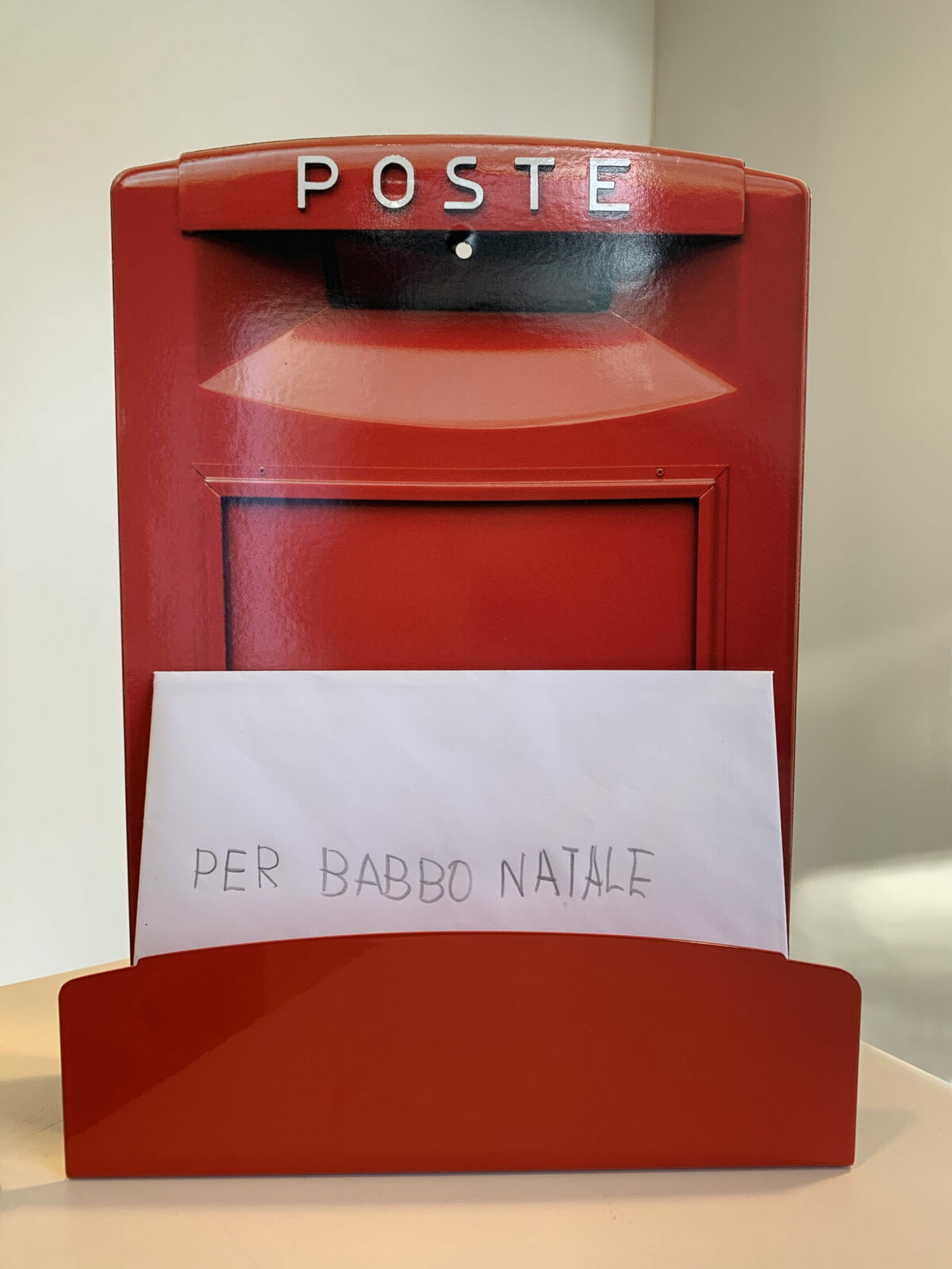 un porta lettere rosso a forma di cassetta postale italiana custodisce una lettera indirizzata a babbo natale