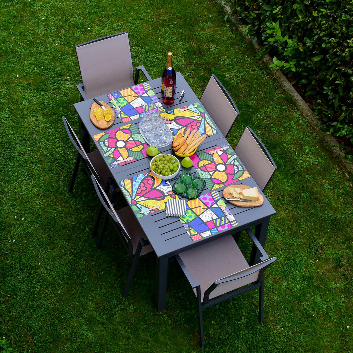 una tavola in giardino è apparecchiata con 6 tovagliette americane quadrate che riportano le immagini di Romero Britto