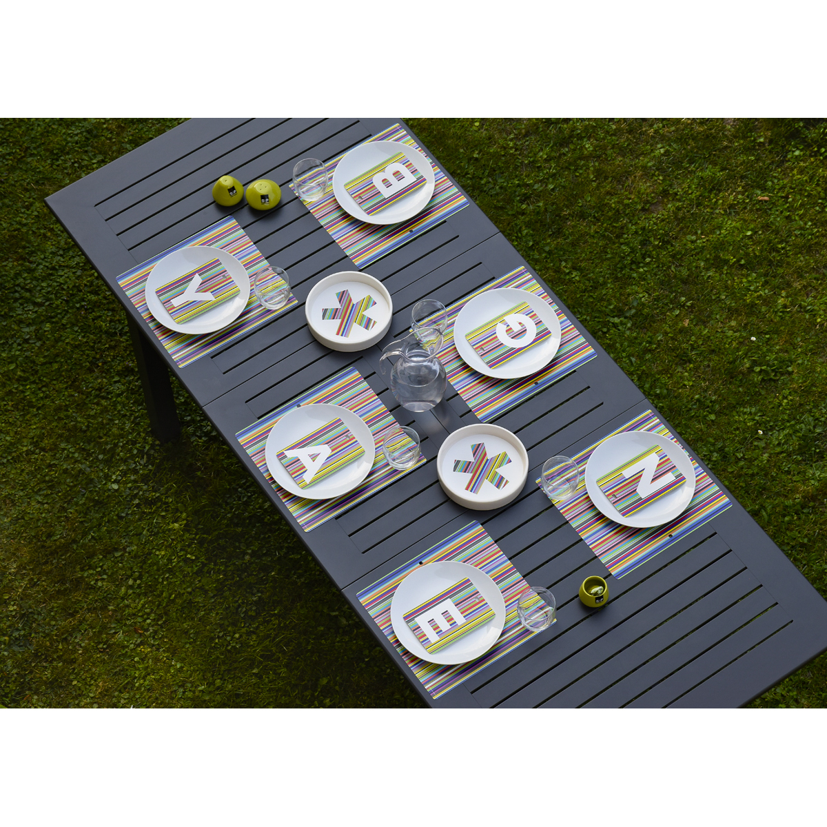 una tavola in giardino è apparecchiata con sei tovagliette americane decoro mille righe colorate