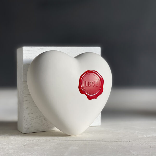 cuore in ceramica bianco opaco con un sigillo in ceralacca rosso con la scritta Love