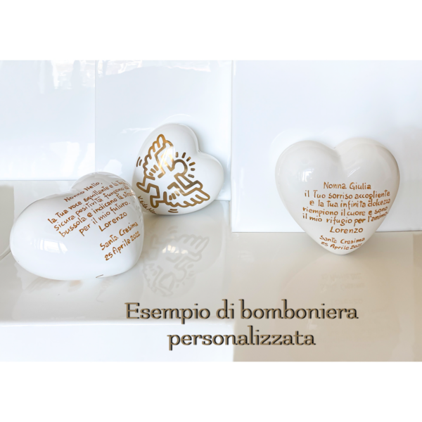 un cuore di ceramica bianco tridimensionale è decorato con un angioletto d'orato e sul retro ha una dedica scritta a mano
