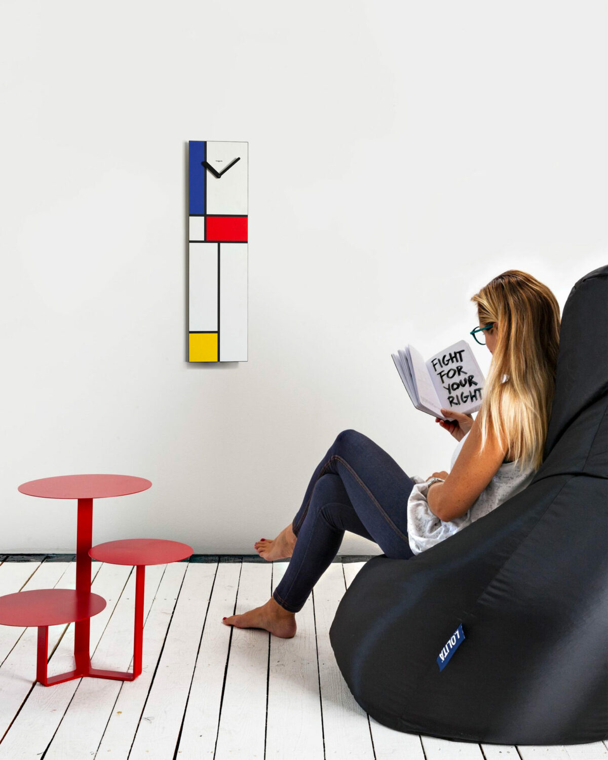 su una parete bianca cattura l'attenzione un orologio verticale ispirato alle geometrie e i colori di Mondrian.