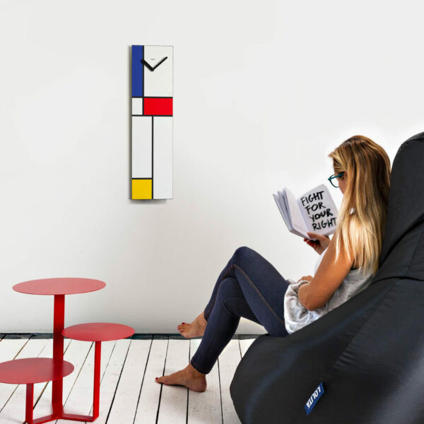 su una parete bianca cattura l'attenzione un orologio verticale ispirato alle geometrie e i colori di Mondrian.