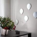 un bouquet di 5 palloncini in vetro formano una composizione di specchi su una parete bianca. I palloncini sono rifiniti anche con un filo bianco