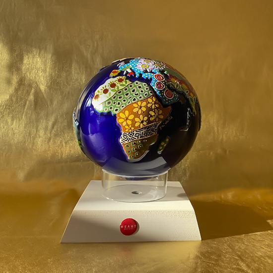 globo in ceramica blu rappresentante la terra con decori a mano sui continenti e appoggiato su una base quadrata in legno bianco