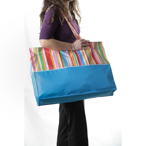 una ragazza porta a tracolla una borsa da spiaggia colorata a righe