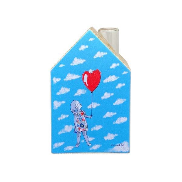 una bimba tiene con un palloncino rosso orna un vaso monofiore a forma stilizzata di casa