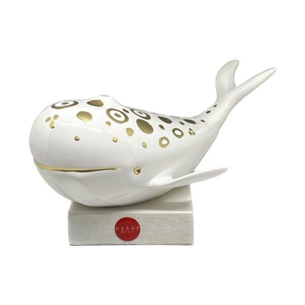 oggetto a forma di balena, bianca, con decorazione dorate su supporto quadrato