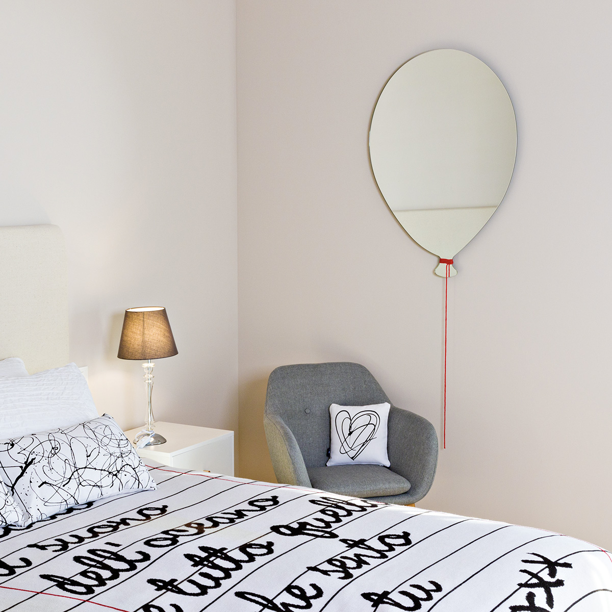 specchio in vetro a forma di palloncino e filo di lana rosso 